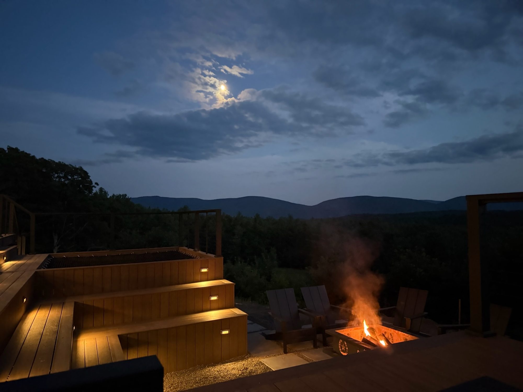 The Le Sommet fire pit and deck under a moonlit Catskill sky
