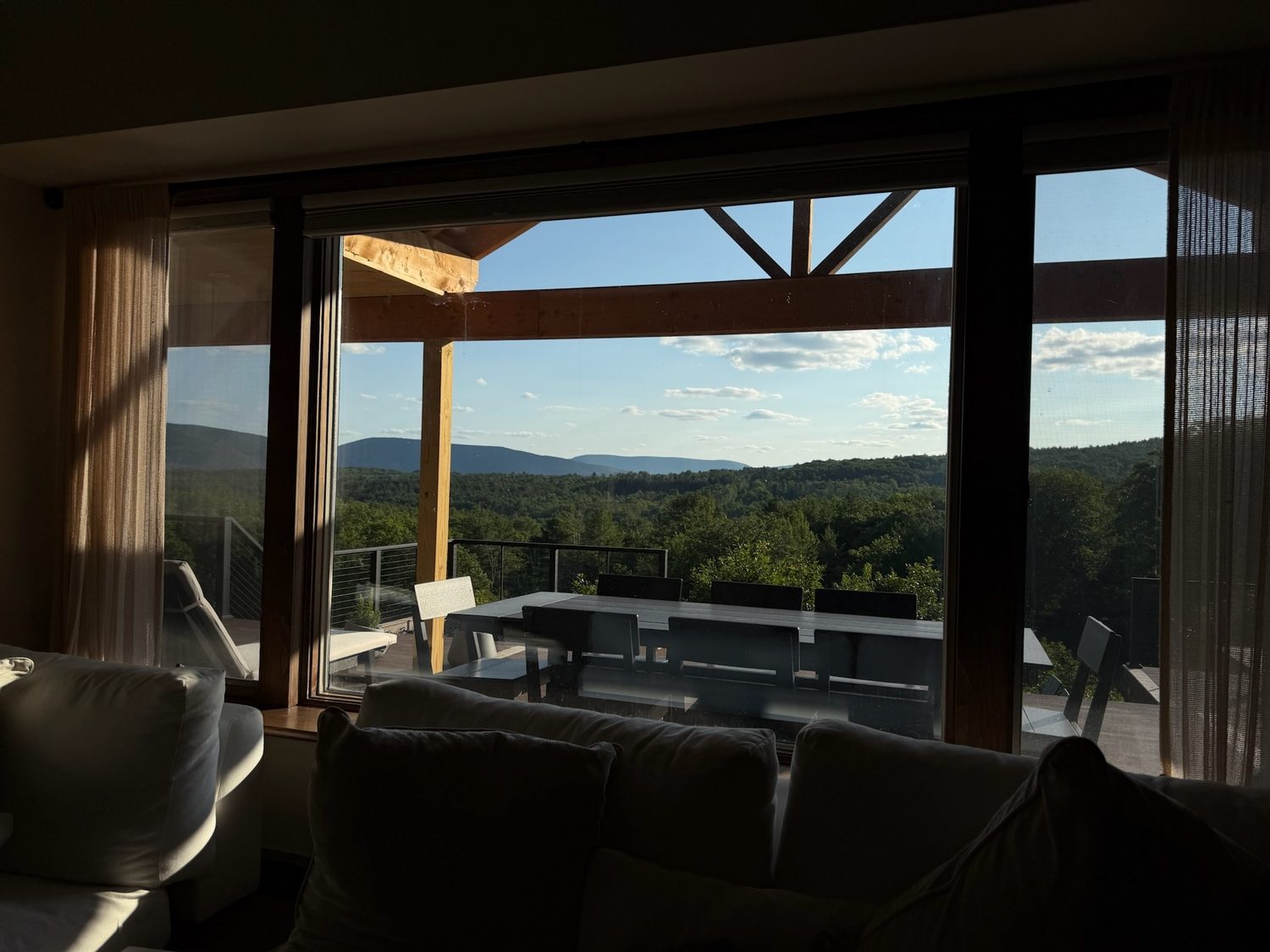 The outdoor dining table on the deck framed by the living room windows and the mountain view